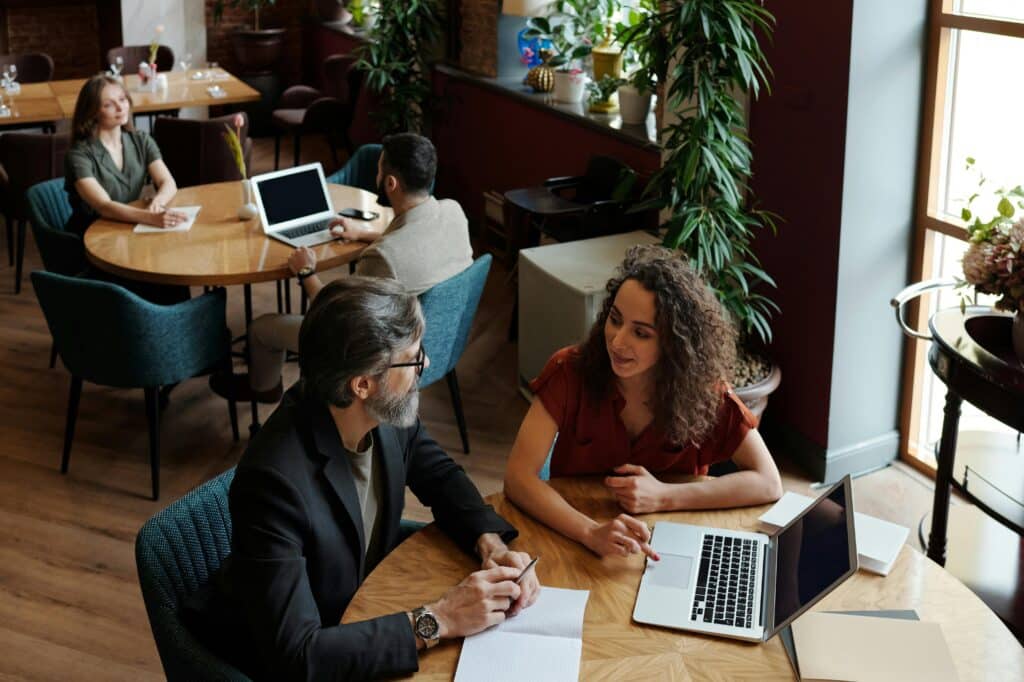 Professionals engaging in a collaborative meeting in a cozy café setting, discussing business projects.